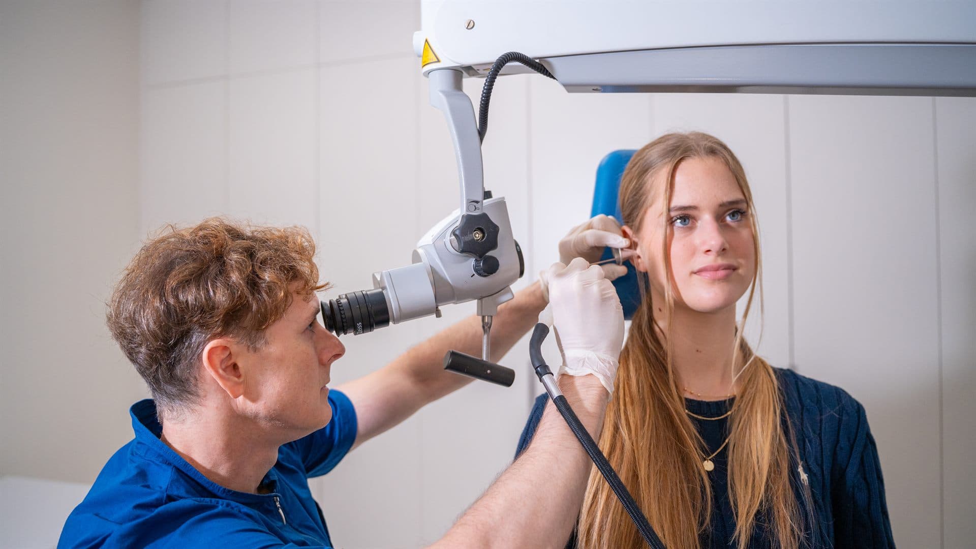 ORL specialist pregleduje pacientkino uho z otomikroskopom v ambulanti GM-O
